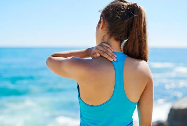 Woman standing in front the ocean with a shoulder pain